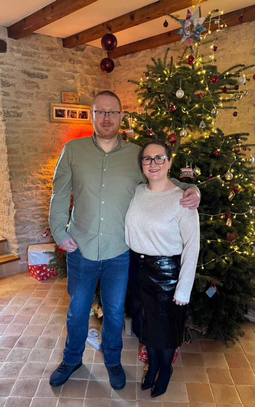 Iain and Claire by the Christmas tree in a stone cottage